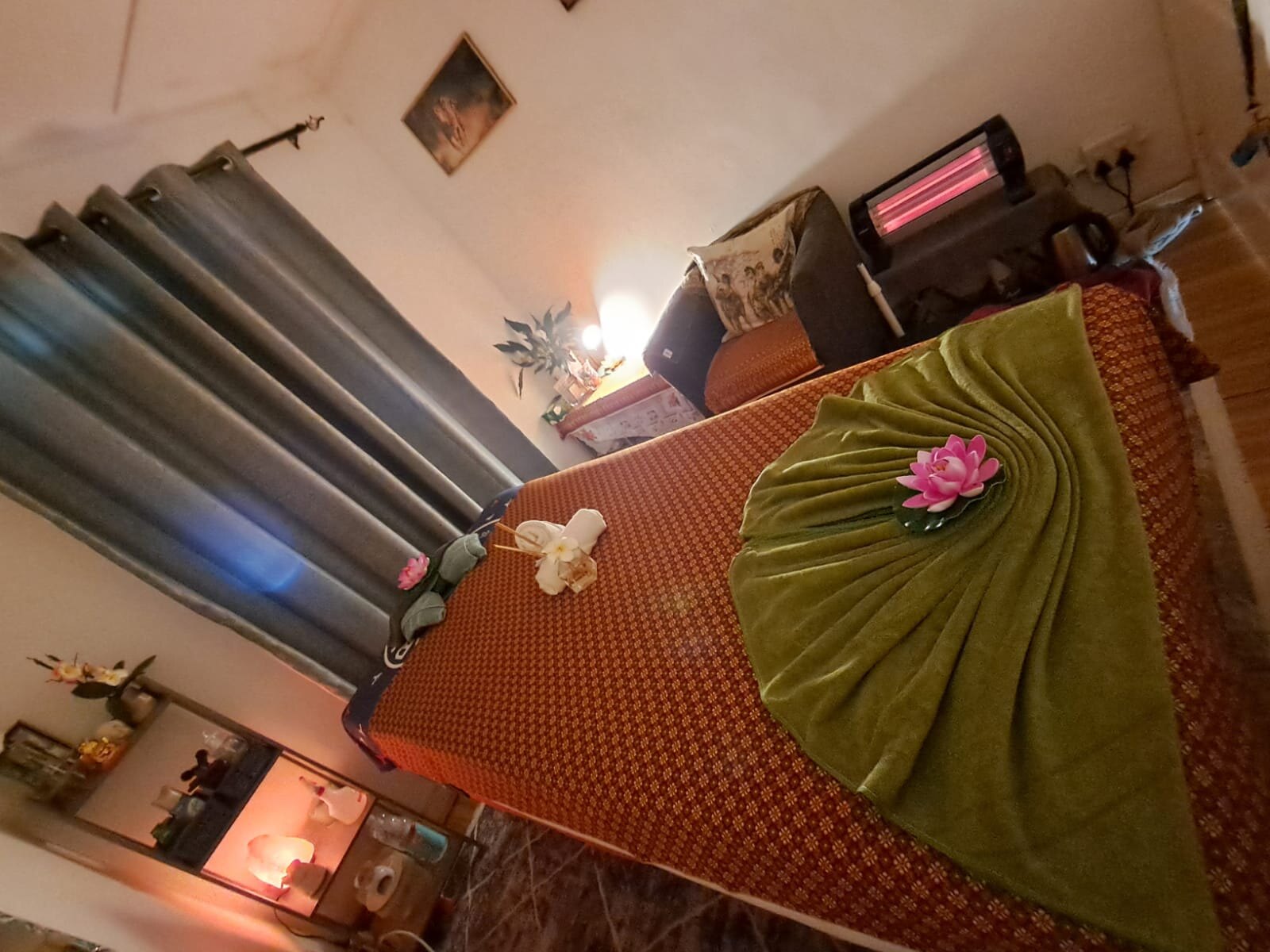 Treatment room with a Thai massage bed dressed in green and gold with a lotus flower